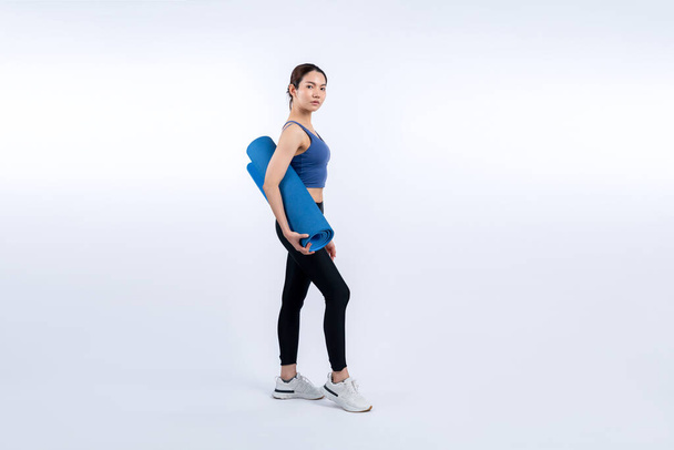 Młoda atrakcyjna azjatycka kobieta portret w odzieży sportowej z maty treningowej. Zdrowe ćwiczenia i rutynowa koncepcja stylu życia treningu. Studio nakręciło odizolowane tło. Energiczny - Zdjęcie, obraz