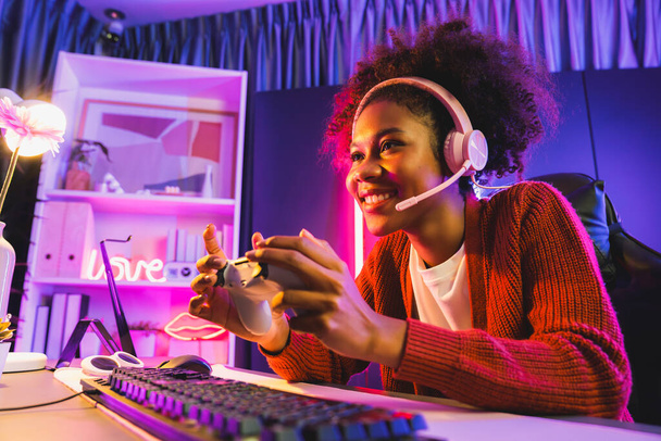 Afrikkalainen amerikkalainen tyttö serpentiini pelaa verkossa taistelevat Esport ammattitaitoinen joukkue yllään kuulokkeet neon väri valaistus huone. Puhuminen muut pelaajat höyläys strategioita voittaa kilpailijoita. Maustevalmistaja. - Valokuva, kuva