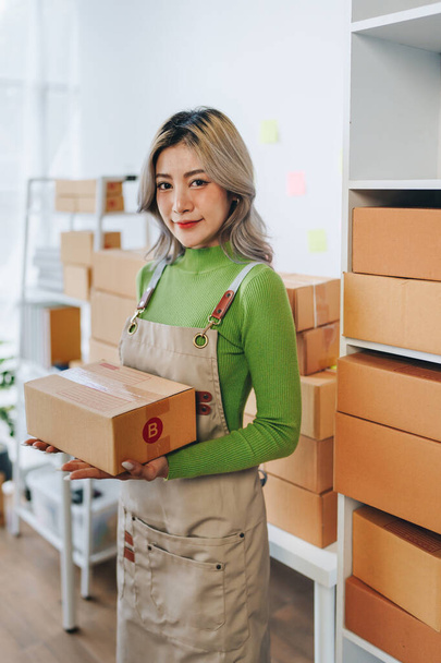 Rozpoczęcie działalności przez małego przedsiębiorcę niezależnego azjatyckiego sprzedawcy internetowego pakującego produkty do wysłania klientom i koncepcja dostawy dla MŚP. - Zdjęcie, obraz