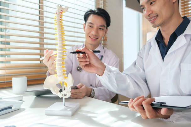 Ortopedové poukazující na model páteře mluví o diagnóze pacientů na lékařské ordinaci. - Fotografie, Obrázek
