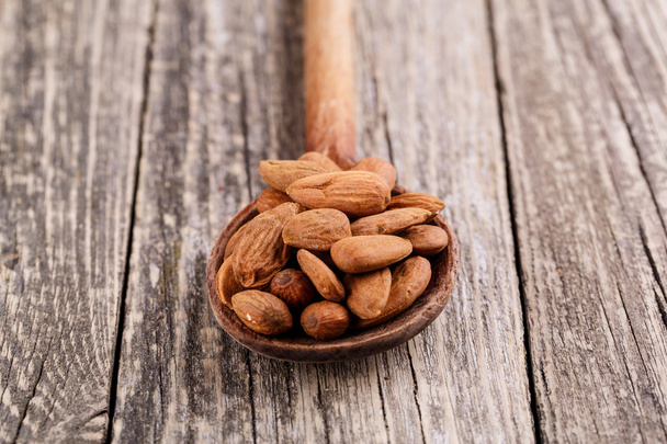 Almonds on a spoon on a wooden background. - Photo, Image