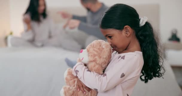 Ouders, vechten en verdrietig meisje kind met een teddybeer in een slaapkamer voor knuffel, ondersteuning of comfort. Stress, familie en mensen ruziën over voogdij, schuld of echtscheiding conflict op een bed met kind met angst. - Video