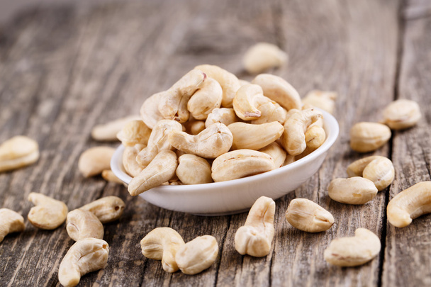 Cashew nuts on a plate on wooden background. - Fotografie, Obrázek