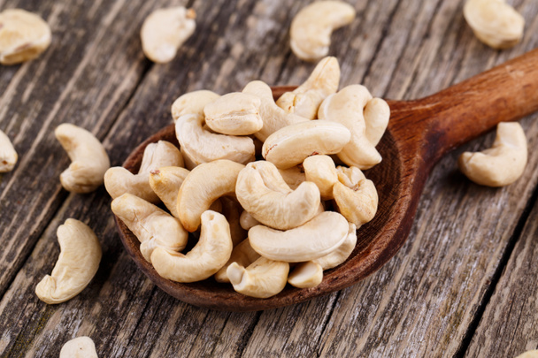 Cashew nuts on a spoon on wooden background. - Fotografie, Obrázek