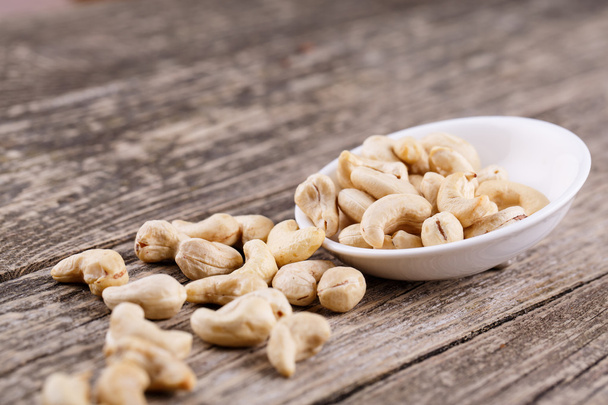 Cashew nuts on a plate on wooden background. - Valokuva, kuva