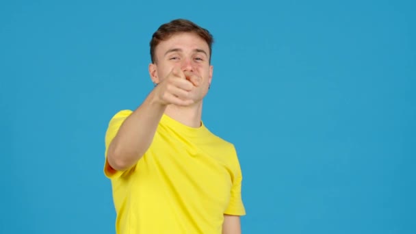 Young positive man doing heart or love shape with hands isolated on blue background. - Footage, Video