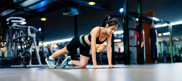 Mladá asijská žena trénink prkno pozici ve fitness centru. Zdravý a kulturista koncept - Fotografie, Obrázek