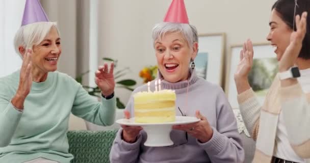 バースデーパーティー,ケーキ,または家のリビングルームの友人とろうそくを吹き飛ばす上級女性と拍手. お祝い,マイルストーン,そして定年退職イベントを楽しんでいる成熟した人とつながる. - 映像、動画