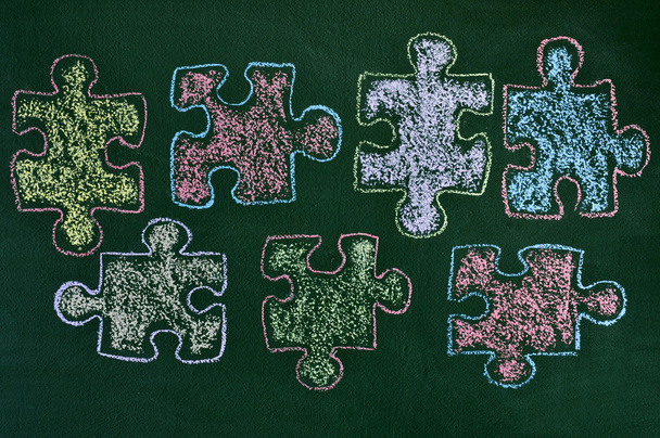 Puzzleteile in verschiedenen Farben auf einer Tafel - Foto, Bild