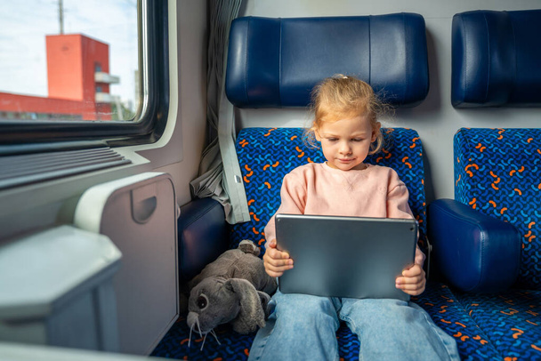 Little girl using digital tablet during traveling by railway in Germany, Europe. High quality photo - Photo, Image