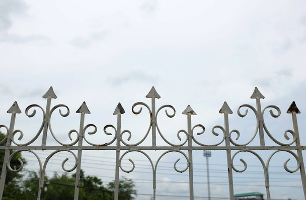 Nahaufnahme, selektiver Fokus Schöner weißer schmiedeeiserner Zaun und verschiedene Dekorationen schützend und Himmelshintergrund - Foto, Bild