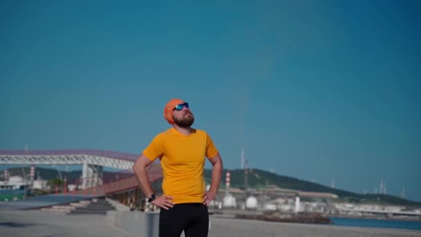 Тело позитивного человека в спортивной одежде делает разминку мышц и суставов перед выполнением подготовки тренировки для бега марафона солнечный день беговой дорожки пальмовый фон - Кадры, видео