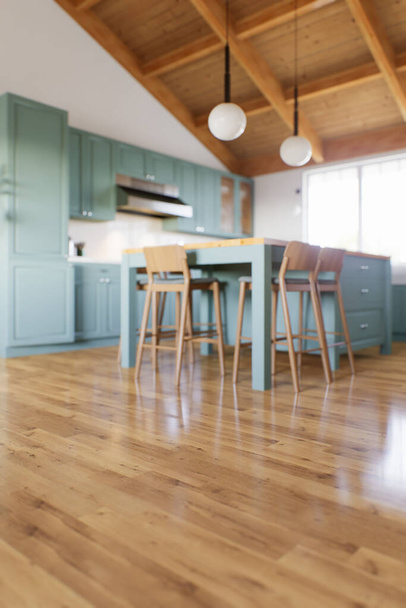 Die große grüne Küche ist aus dem Fokus geraten. Grüne Küche Interieur in Bokeh mit einem Schwerpunkt auf Holzboden. 3D-Rendering - Foto, Bild