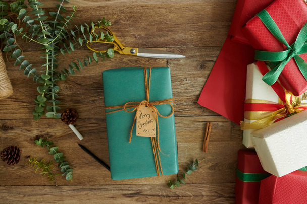 Vánoční dárek zabalený v tyrkysovém papíru na stole, pohled shora - Fotografie, Obrázek