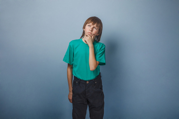 Niño, adolescente, doce años en camisa verde, sonrió soñadoramente
 - Foto, Imagen