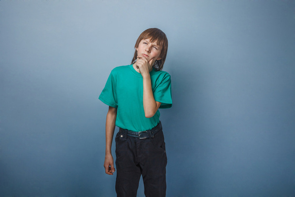 Το αγόρι, το έφηβος, δώδεκα χρόνια σε ένα πράσινο πουκάμισο, χαμογέλασε απλανές βλέμμα - Φωτογραφία, εικόνα