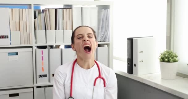 Νεαρή γυναίκα γιατρός χασμουρητό στο γραφείο 4k ταινία αργή κίνηση. Ώρες εργασίας για την έννοια του ιατρικού προσωπικού - Πλάνα, βίντεο