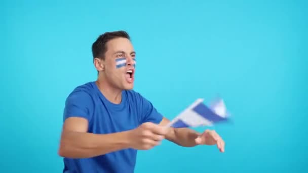 Video in studio with chroma of a man cheering for El Salvador screaming and waving a national flag, looking away to the copy space in blank - Footage, Video