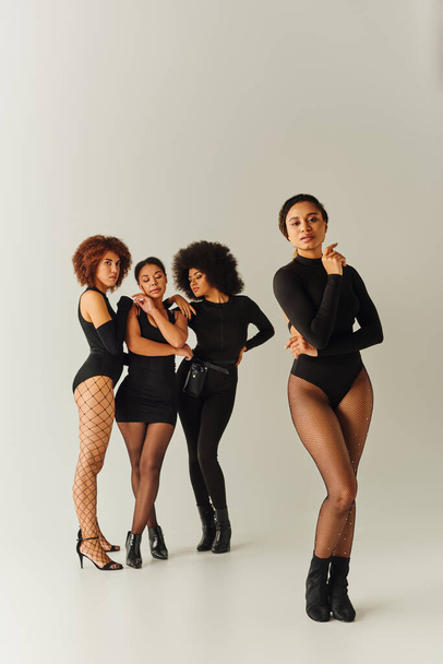 beautiful african american female friends posing together in sexy black attires, fashion concept - Photo, Image