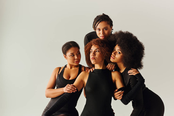 attraktive afrikanisch-amerikanische Frauen in schwarzen verführerischen Kleidern posieren auf schwarzem Würfel, Modekonzept - Foto, Bild