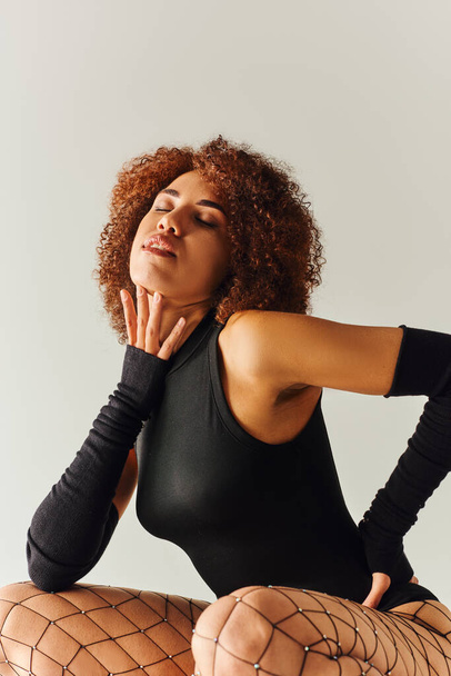 attraktive afrikanisch-amerikanische Frau in Netzstrumpfhosen und sexy Body posiert verführerisch, Mode - Foto, Bild