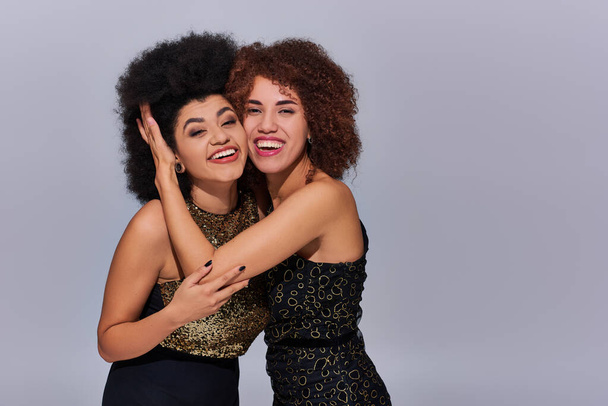 две довольно счастливые африканские американские женщины в праздничных нарядах тусуются вместе, концепция моды - Фото, изображение