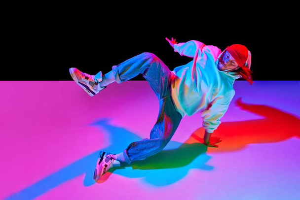 Athletic young man in motion, dancing breakdance isolated over black studio background in neon light. Concept of contemporary dance, street style, fashion, hobby, youth. Ad - Photo, Image