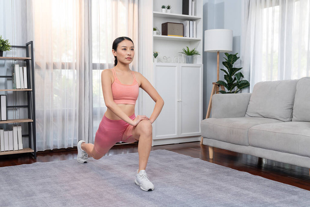 Młoda, atrakcyjna Azjatka w sportowej odzieży rozciągająca się przed ćwiczeniami fitness. Trening ciała domowego ze zdrową atletyczną kobietą rozgrzewającą się. Energiczny - Zdjęcie, obraz