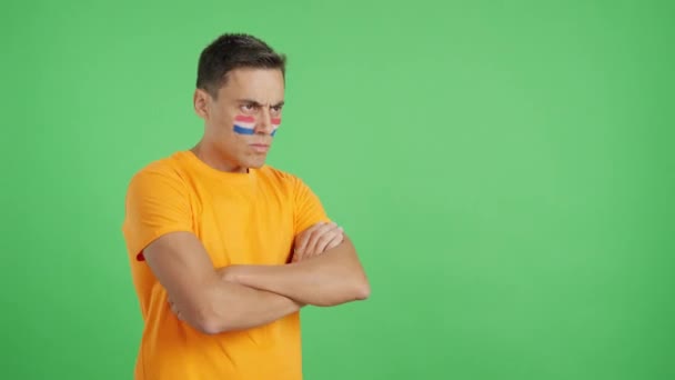 Video im Studio mit dem Chroma eines Mannes mit holländischer Flagge im Gesicht, der mit ernstem Gesichtsausdruck wegschaut - Filmmaterial, Video