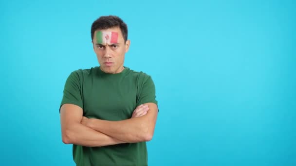 Video en estudio con croma de un hombre digno y serio con bandera mexicana pintado en la cara mirando a la cámara con dignidad - Metraje, vídeo