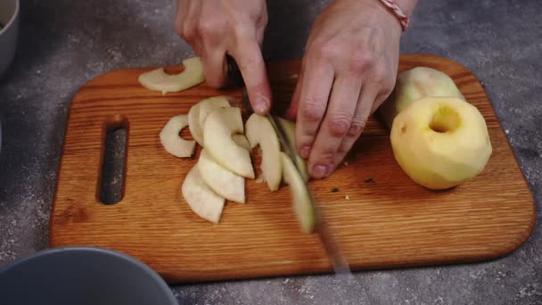 Γυναίκα χέρια τεμαχίζοντας μήλα σε μια ξύλινη σανίδα κοπής γκρο πλαν σε ένα τραπέζι κουζίνας - Πλάνα, βίντεο
