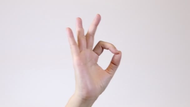 Crop vrouw toont OK gebaar. Statische schot van anonieme vrouw gebaren oke met opgeheven arm tegen levendige witte achtergrond - Video