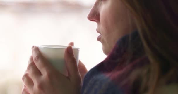 Mujer linda con una taza blanca bebe chocolate caliente, té o café en invierno nevado al aire libre. Imágenes de alta calidad 4k - Metraje, vídeo
