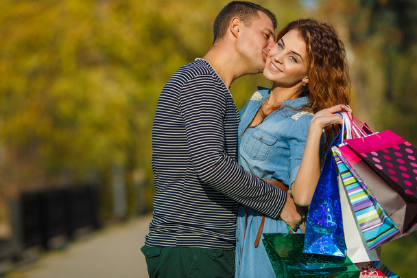 Happy νεαρό ζευγάρι με μια χάρτινη σακούλα σε ένα πάρκο φθινόπωρο. - Φωτογραφία, εικόνα