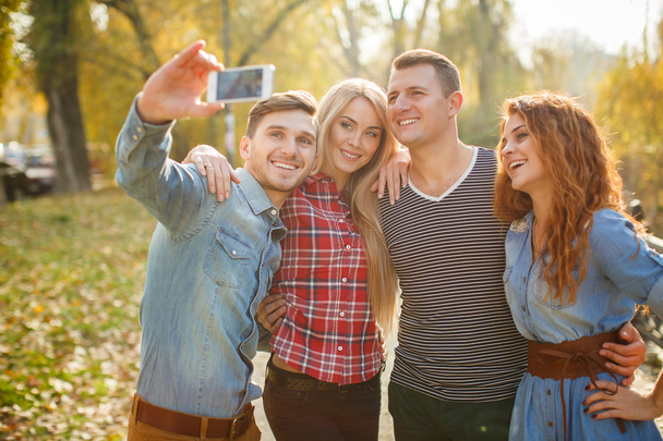 Friends are photographed with a smartphone in the Park. - Foto, Imagen