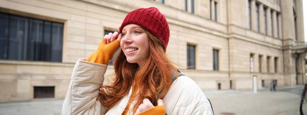 Tourism and travelling. Young redhead woman smiling, tourist walking with backpack around city centre, sightseeing, holds backpack with paper map. - Foto, Bild
