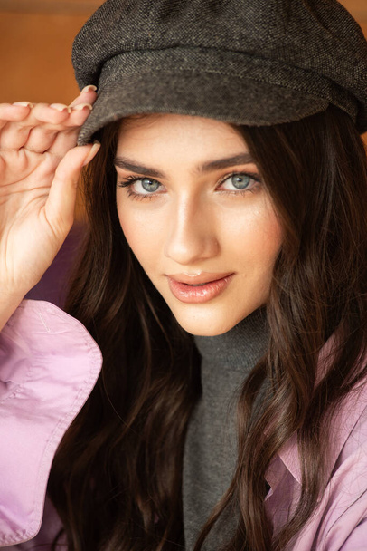 bella giovane donna in elegante berretto e berretto su sfondo beige - Foto, immagini