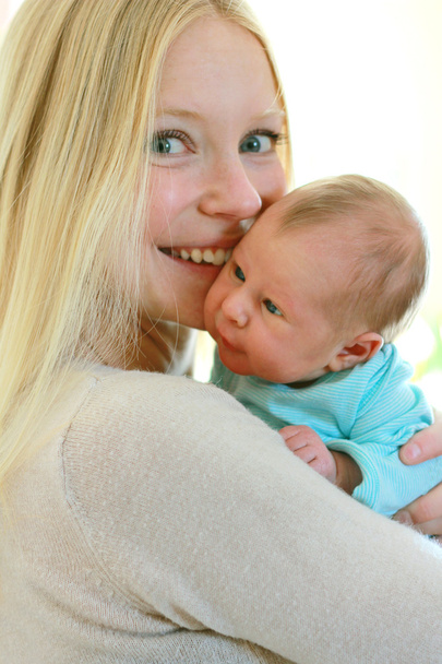 Счастливая молодая мать держит на руках милого новорожденного ребенка
 - Фото, изображение