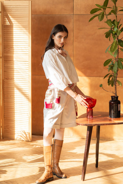 молода жінка з червоною чашкою в кімнаті - Фото, зображення