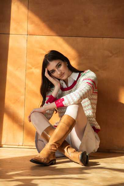 молодая женщина в теплых свитерах и носках позирует возле деревянной стены - Фото, изображение