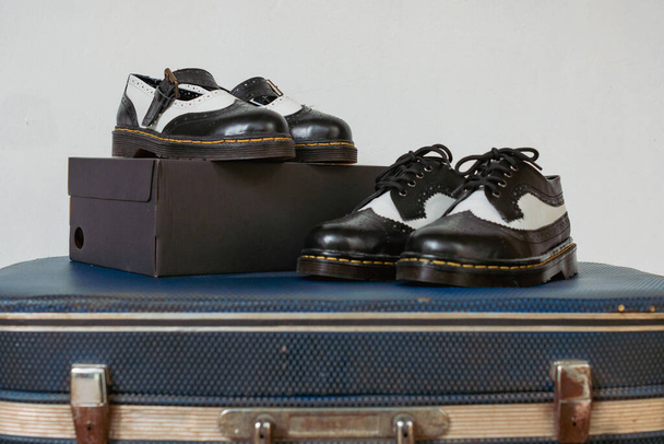 Klasyczne dwutonowe buty brogue Wingtip i dwutonowe buty Mary Jane wykonane z prawdziwej skóry wyświetlane na brązowej tkaninie z klasycznym wzorem. Zdjęcie koncepcyjne pary butów w stylu vintage - Zdjęcie, obraz