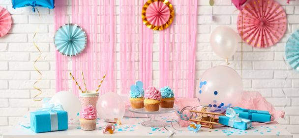 Lekkere cupcakes met geschenken voor geslacht onthullen feest op tafel in de kamer - Foto, afbeelding