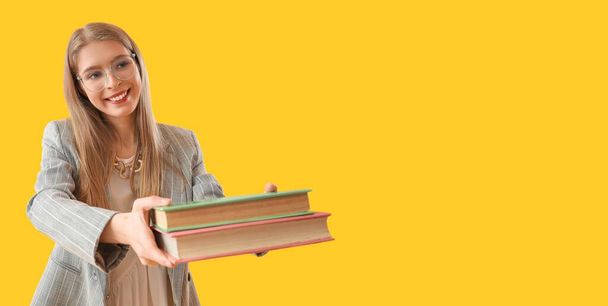Hezká mladá žena drží knihy na žlutém pozadí s prostorem pro text - Fotografie, Obrázek
