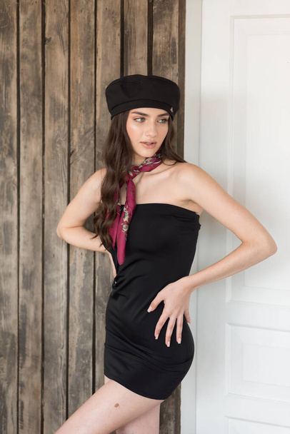 schönes Mädchen in schwarzem Kleid und schwarzem Hut posiert im Studio. - Foto, Bild