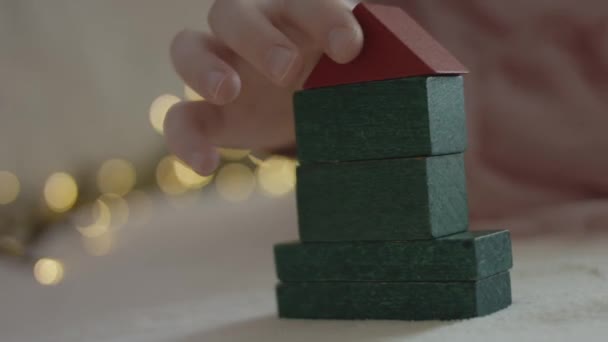 Een klein meisje dat een kerstboom bouwt met gekleurde bouwdelen. close-up schieten. - Video