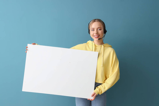Vrouwelijke technische ondersteuning agent met blanco poster op blauwe achtergrond - Foto, afbeelding