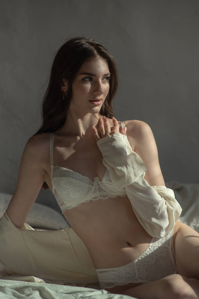 sensual mulher morena com renda branca em rendas lingerie posando no quarto - Foto, Imagem