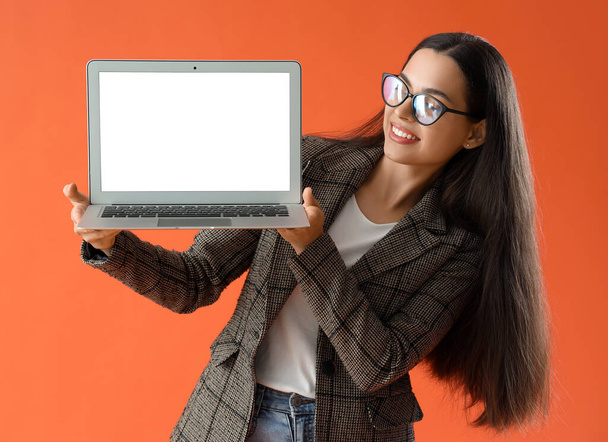Csinos fiatal női programozó gazdaság laptop üres képernyő narancssárga háttér - Fotó, kép