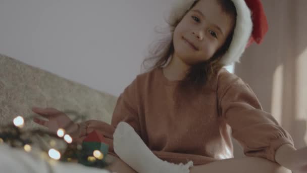 Ein kleines Mädchen baute einen Weihnachtsbaum aus farbigen Bauteilen. Blick in die Kamera - Filmmaterial, Video