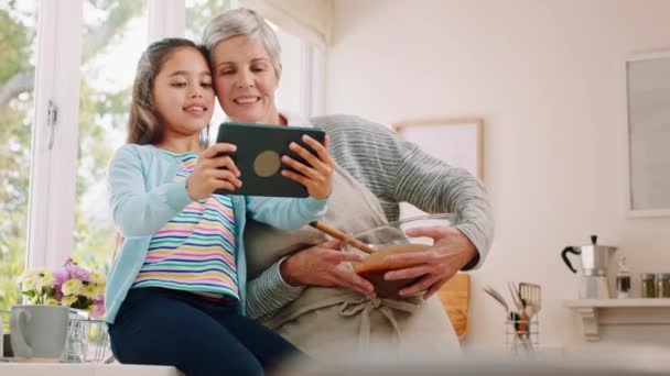 Tablet selfie, ruoanlaitto ja lapsi isoäidin kanssa keittiössä viestintään, mobiilisovellukseen ja sosiaaliseen mediaan. Teknologia, digitaalinen valokuva ja tyttö vanhempi nainen leipoo rakkaudella ja hymyllä. - Materiaali, video
